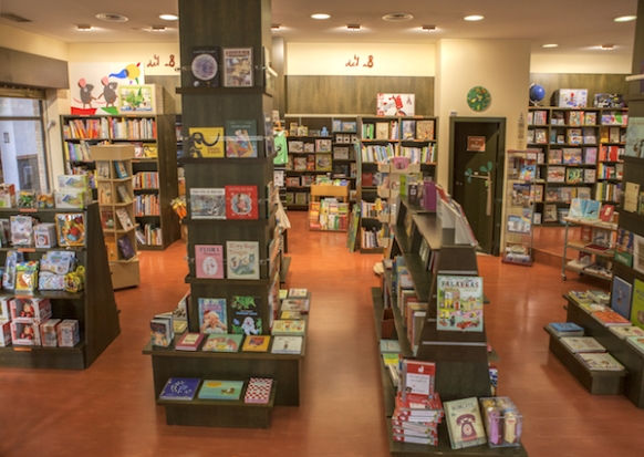 Interior de la librería Rayuela en Sevilla, con estantes llenos de libros organizados por géneros y un ambiente cálido.