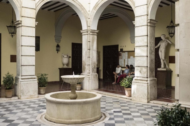 Fuente ubicada en el patio interior de la Biblioteca de la Universidad de Sevilla, en el histórico edificio de la Fábrica de Tabacos. La estructura de la fuente resalta con su diseño clásico, rodeada de columnas y detalles arquitectónicos tradicionales.