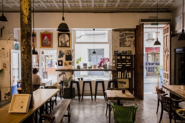 Interior de la librería 'Un Gato en Bicicleta' en Sevilla, con estanterías de madera repletas de libros, arte y decoración única. Ambiente acogedor y creativo que invita a descubrir libros de autor y ediciones especiales en un espacio cultural alternativo.